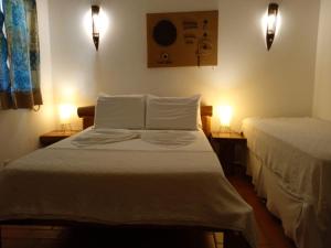 a bedroom with two beds and two lights on the wall at Pousada Chez Loran lagoa do paraiso in Jijoca de Jericoacoara