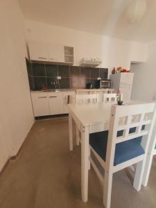 a white kitchen with a white table and chairs at Departamento Génesis, 1er piso in Chilecito