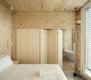 a bedroom with a white bed and a tub at Hotel Amiuka in O Pedrouzo