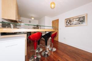 una cucina con sgabelli rossi e bancone di Exhilarating 2BD Flat with Outdoor Patio Dublin! a Dublino