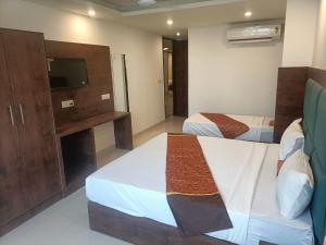 a hotel room with two beds and a tv at Hotel The Tark Near IGI Airport Delhi in New Delhi