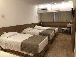 ein Hotelzimmer mit 3 Betten und einem Stuhl in der Unterkunft South American Copacabana Hotel in Rio de Janeiro