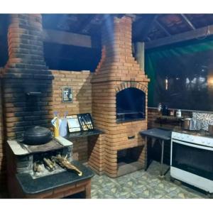La cocina está equipada con horno de ladrillo y mesa. en Sítio Vale dos Reis, en Resende