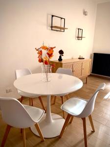 Biały stół z białymi krzesłami i waza z kwiatami w obiekcie Casalago Holiday Home w mieście Ronciglione