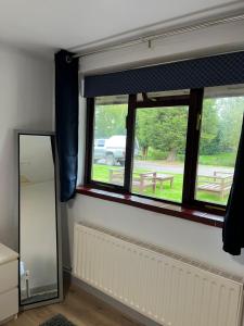 a room with two windows and a mirror at Pinewood Lodge in Ibstock