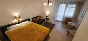 a bedroom with a large bed with a yellow blanket at City break Park Studio Bucharest in Bucharest