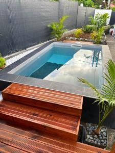 une petite piscine avec une terrasse en bois et une table en bois dans l'établissement Villa de 2 chambres avec vue sur la ville piscine privee et jardin clos a Le Lamentin, au Lamentin