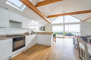 a kitchen with white cabinets and a large window at Fisherman's Croft Your Dream Getaway Awaits in Pevensey +35 photos