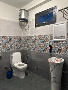 a bathroom with a toilet and a tv on the wall at Rare House in Kalgha