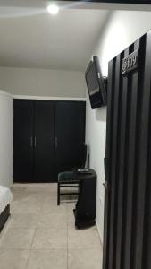 Habitación con una habitación con armarios negros y TV. en Hotel Bellagio en Barrancabermeja