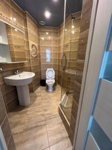 a bathroom with a toilet and a sink and a shower at Three Dolphins Hotel in Aktau