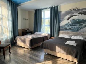 a bedroom with two beds and a painting of dolphins at Three Dolphins Hotel in Aktau