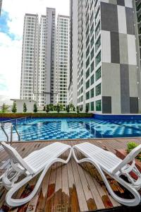 two white chairs sitting on a deck near a swimming pool at D'Summit Tropika - 2 Rooms 4 Pax, Free Parking in Johor Bahru