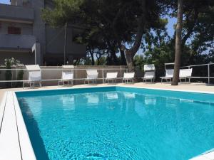 a blue swimming pool with white chairs at La Villa Della Meda in Taranto