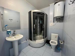 ein Bad mit einer Dusche, einem WC und einem Waschbecken in der Unterkunft Three Dolphins Hotel in Aqtau
