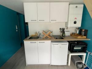 a kitchen with white cabinets and a sink at Charmant Studio - Jacuzzi/Jardin in Andernos-les-Bains