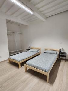 two beds in a white room with wooden floors at Come a casa vostra in Lucca