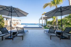 a patio with chairs and umbrellas next to a pool at 1 Homes Preview Cabo in Cabo San Lucas
