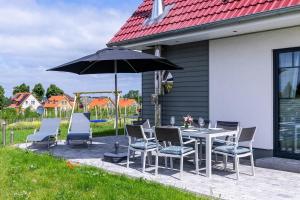 un patio con mesa, sillas y sombrilla en Ferienhaus Fine, en Gross Schwansee