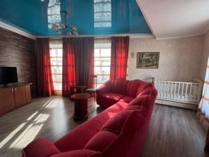 a living room with a red couch and a crib at Three Dolphins Hotel in Aktau