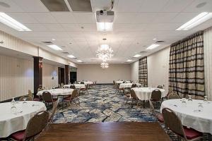 uma sala de banquetes com mesas e cadeiras com toalhas de mesa brancas em Wingate by Wyndham Macon em Macon