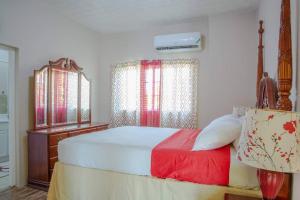een slaapkamer met een bed, een dressoir en ramen bij Savan Suite - Caribbean Estates - Gated Community in Portmore