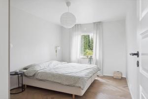 a white bedroom with a bed and a window at Sjönära hus med grillstuga & vacker omgivning in Gråbo