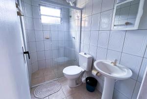 a white bathroom with a toilet and a sink at Pousada Águas do Embaú in Guarda do Embaú +37 photos