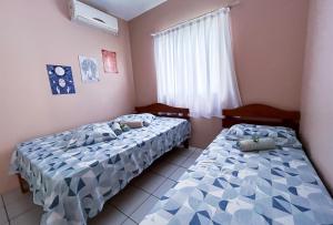 two beds sitting in a room with a window at Pousada Águas do Embaú in Guarda do Embaú