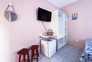 a small kitchen with a small refrigerator and two stools at Pousada Águas do Embaú in Guarda do Embaú