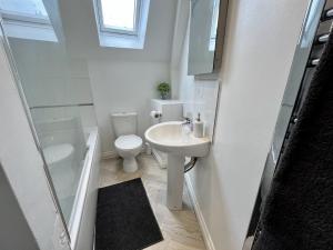 un bagno bianco con un water e un lavandino di The Coach House - with hot tub a St Austell
