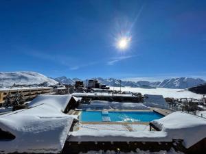 ośrodek wypoczynkowy z basenem pokrytym śniegiem w obiekcie Studio Alpe d'huez w mieście LʼHuez