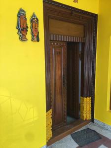una parete gialla con una porta in legno su un edificio di Major Madi Residency a Pondicherry