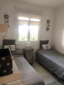 1 dormitorio con 2 camas individuales y ventana en Appart T3 à louer en Andalousie en Chiclana de la Frontera