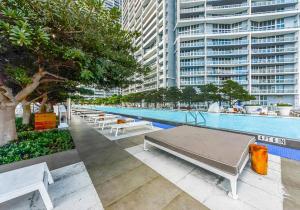 a pool with tables and benches next to a building at Studio at Icon Brickell Luxury Waterfront Building in Miami