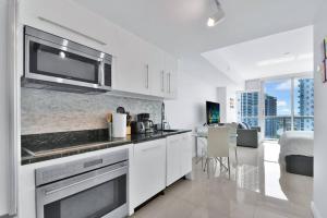 a kitchen with white cabinets and a microwave at Studio at Icon Brickell Luxury Waterfront Building in Miami