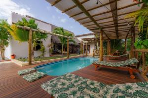 una piscina con terraza de madera y una casa en Villa Pousada 35knots Brasil, en Ponta do Anel