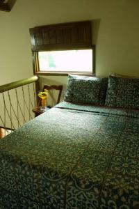 um quarto com uma cama com um edredão verde e uma janela em Casa Néctar em Lençóis