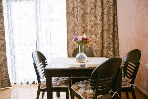 einen Esstisch mit Stühlen und eine Vase aus Blumen in der Unterkunft Ekaterine's Apartments in Batumi