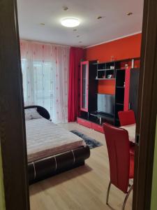 sypialnia z łóżkiem i telewizorem oraz czerwone ściany w obiekcie Apartament Mia w mieście Ocnele Mari
