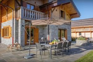 eine Terrasse mit einem Tisch, Stühlen und einem Sonnenschirm in der Unterkunft Chalet Chamaline - OVO Network in Le Grand-Bornand