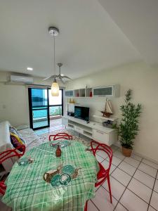 een woonkamer met een tafel en stoelen en een televisie bij Apartamento no Porto Real Resort com vista espetacular p/ 6 adultos e 4 adolescentes in Mangaratiba
