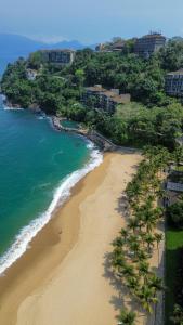 een luchtzicht op een strand met palmbomen en de oceaan bij Apartamento no Porto Real Resort com vista espetacular p/ 6 adultos e 4 adolescentes in Mangaratiba