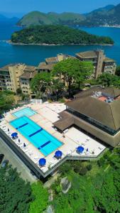 Apartamento no Porto Real Resort com vista espetacular p/ 6 adultos e 4 adolescentes في مانغاراتيبا: اطلالة علوية على مسبح مع مظلات ومبنى
