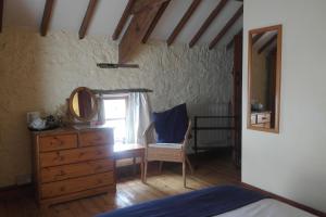a bedroom with a dresser and a mirror and a chair at The Old Barn in Barry