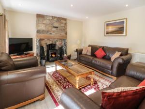 a living room with leather furniture and a fireplace at Buckled Barn in Dumfries