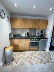 a kitchen with wooden cabinets and a stove at Compact Modern Apartment Single Person or Couple Only in Bangor
