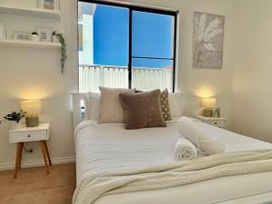 a bedroom with a white bed with a large window at Your Sunny Pool & Ocean Escape in Coogee +30 photos