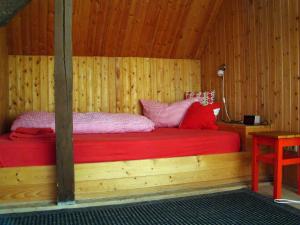 a bedroom with a red bed in a wooden cabin at Alte Ausspanne in Walkendorf