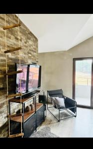 een woonkamer met een tv en een bakstenen muur bij Арт Мезонет Salem in Velingrad
